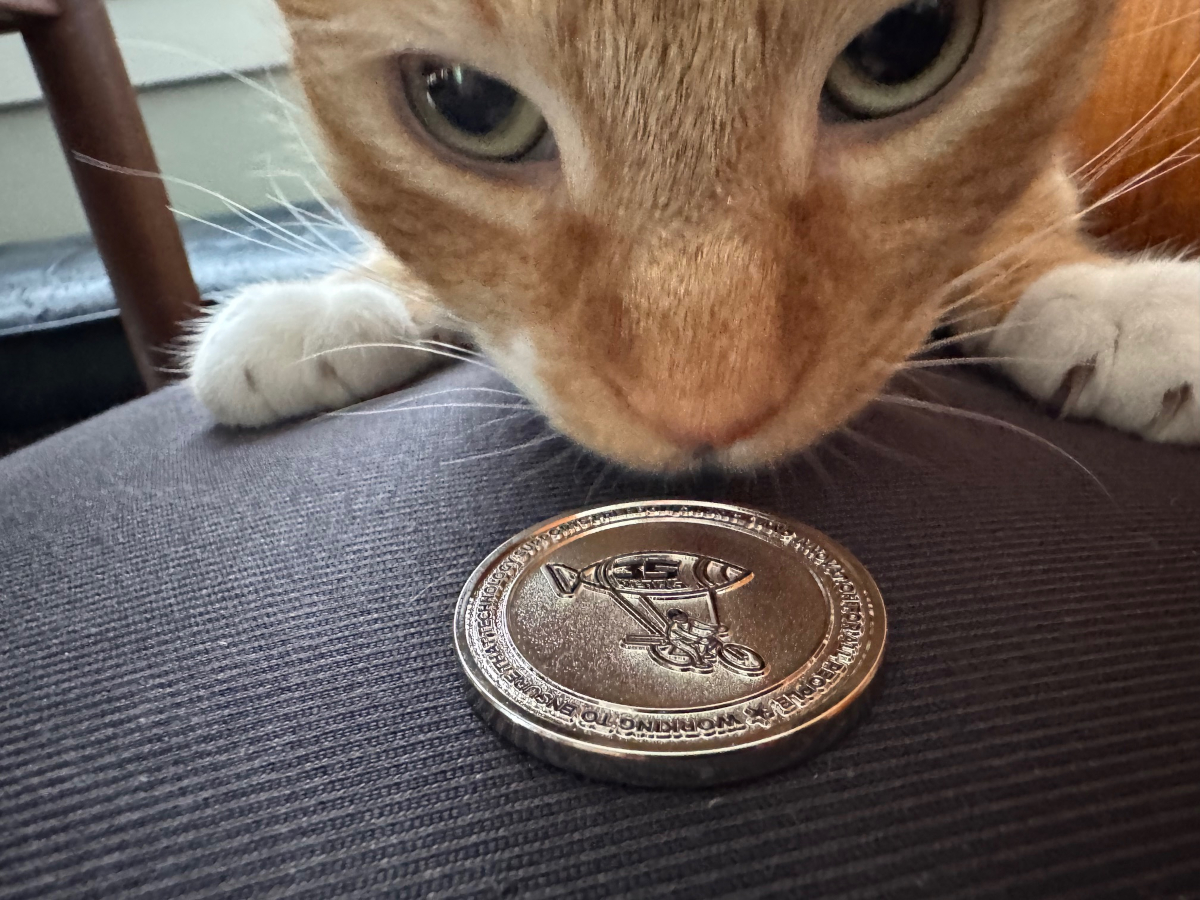 Orange cat inspecting EFF 35th Anniversary Challenge Coin